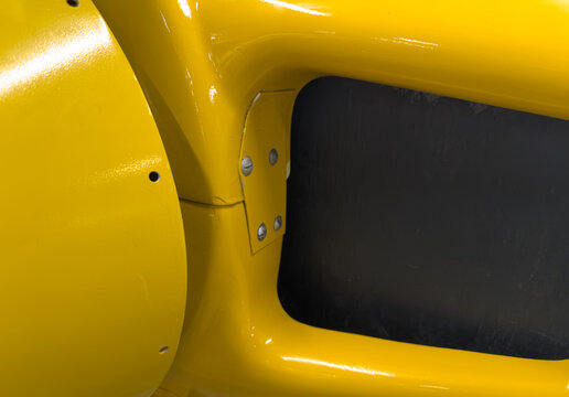 Close-up of bright yellow nose area of an old plane or machine
