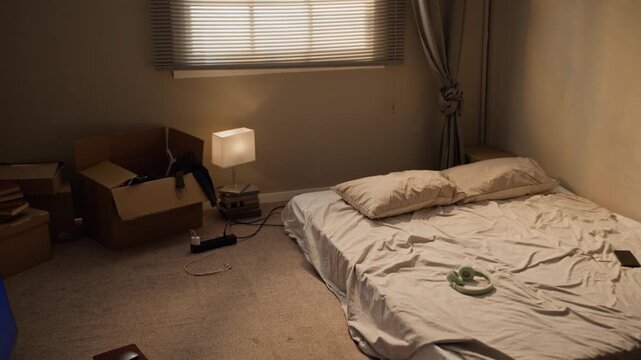 Camera tilting up across minimalist studio apartment showing mattress on floor and cardboard boxes. Footage suitable for student housing and relocation advertising