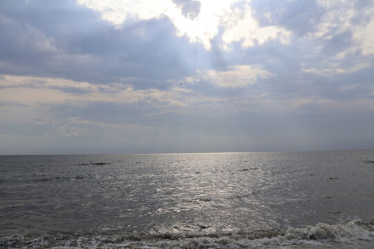 Evening sun casting a warm glow through the clouds over a calm bay.