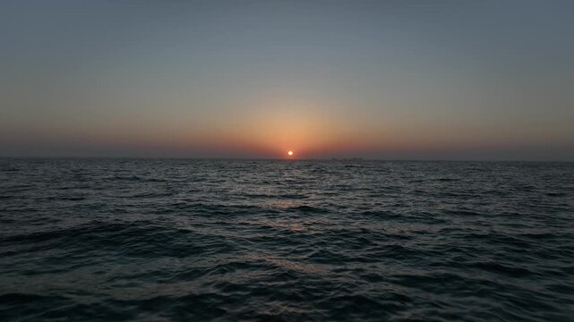 海面を進み黄金色の夕陽に向かって進むシネマティック空撮