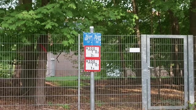 Sign for bus route and stop in a forested area near a fence