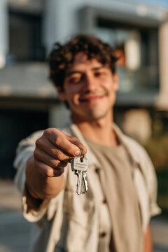Man key house smile focus hand real estate outdoor casual happiness young man holding key toward camera with blurred face in background symbolizing new home and successful purchase