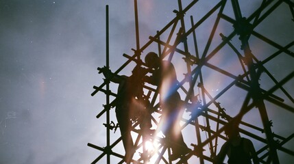 Obraz premium Silhouette of Construction Workers on Metal Scaffolding at Sunset