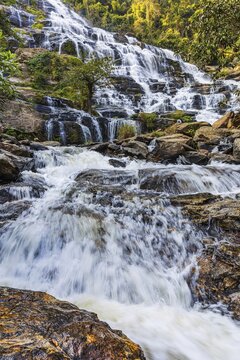 Mae Ya waterfall with cascading flowing water surrounded by lush tropical vegetation, near Doi Inthanon National Park, Chiang Mai Province, Thailand