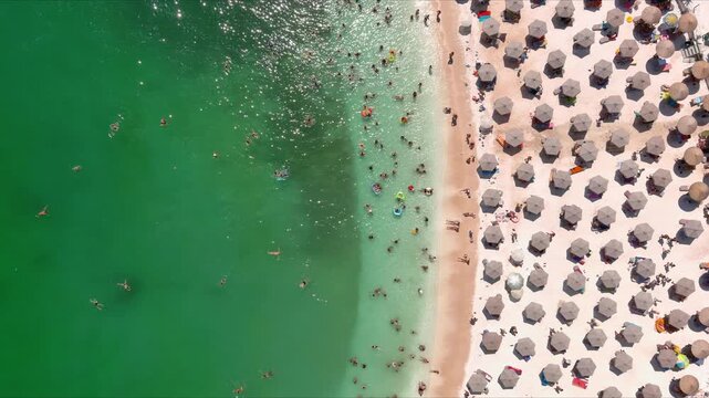 Aerial view of crowded beach with numerous umbrellas and people swimming in turquoise water, Thasos, Greece.