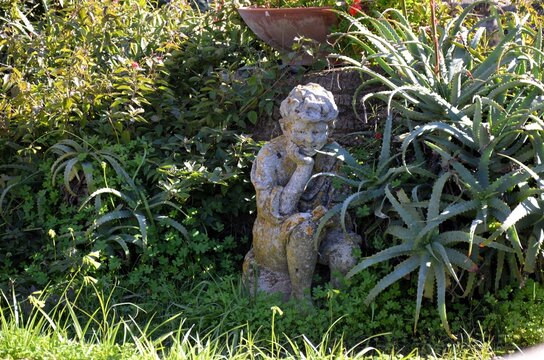 pensive putto nestled among the aloe plants and clovers of the Villa Comunale in Caltagirone
