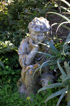 pensive putto nestled among the aloe plants and clovers of the Villa Comunale in Caltagirone