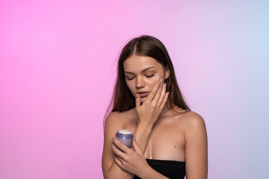 Woman applying face cream, moisturizing her skin for beauty and wellness. Skincare routine for young girl