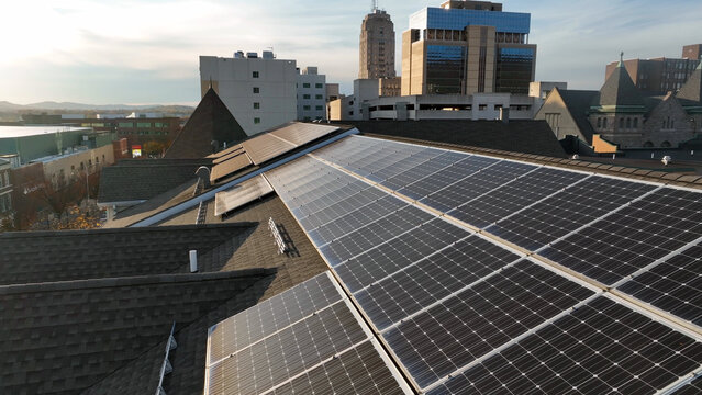 Aerial view of solar panels installed on a residential rooftop with urban buildings in the background in Reading, Pennsylvania, United States.