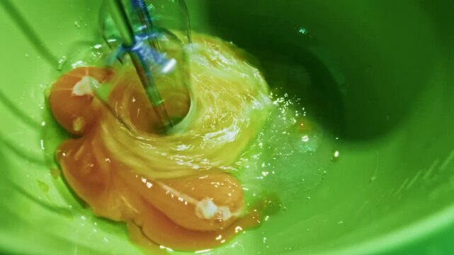 Electric Hand Mixer Whisking Raw Fresh Eggs Yolks Whites In Bowl. 
Process Omelet 