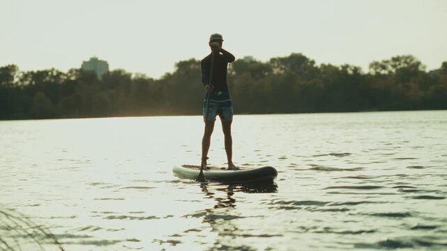 Stand Up Paddleboarder Paddling On Calm Water Lake At Sunset. Active Lifestyle