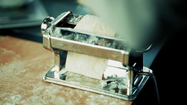 Rolling Fresh Raw Dough Through Pasta Maker Machine. Preparing Homemade Italian Noodles