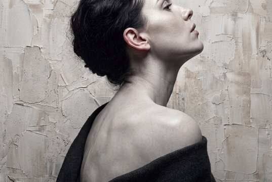 Monochrome side portrait of a woman against textured plaster
