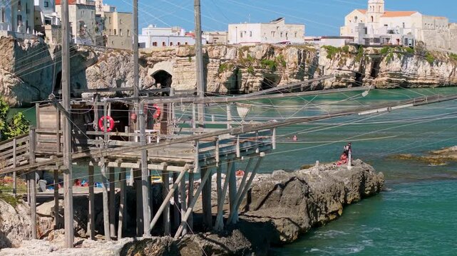 Vieste Gargano Puglia Italy 4K drone video. 70mm telephoto trabucco reveal of historic white town on rocky cliff. Authentic traditional fishing net stock footage
