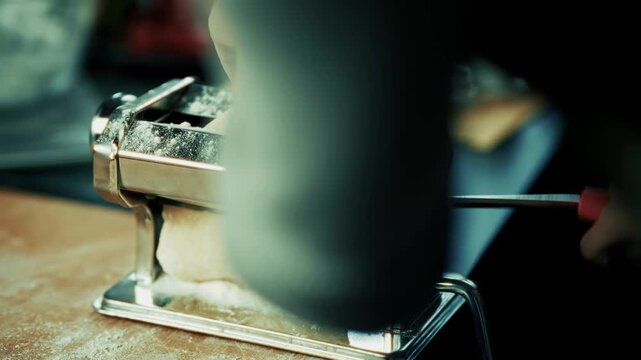 Rolling Fresh Raw Dough Through Pasta Machine. Making Homemade Italian Pasta Noodles