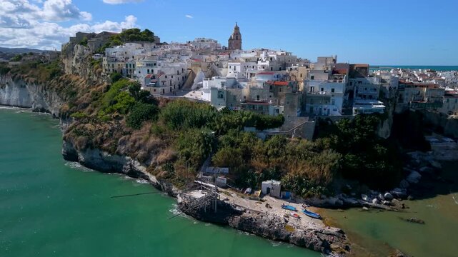 Vieste Gargano Puglia Italy historic white cliff town cinematic drone rotation small fishing boats adriatic sea and trabucco travel 4k video. Authentic southern italian coastal village