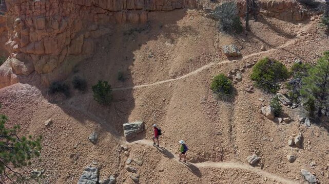 Aerial view of man and woman hiking on the Buckhorn trail surrounded by hoodoos in Bryce Canyon, Utah, enjoying the natural landscape.