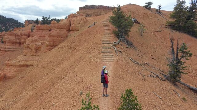 Man and woman hike on the Buckhorn trail with hoodoos around them near Bryce Canyon in Utah on a clear day