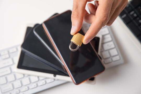 Male hand with a padlock, phones and computer keyboard. Internet and computer security