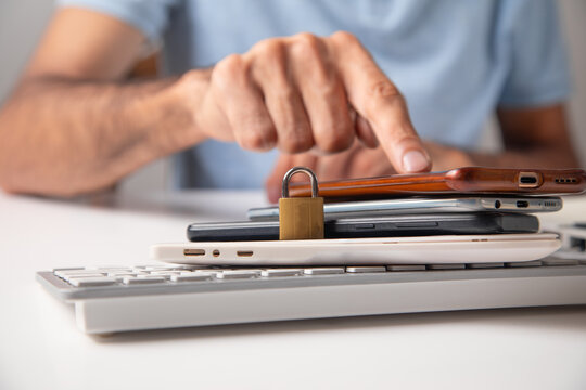 Male hand with a padlock, phones and computer keyboard. Internet and computer security