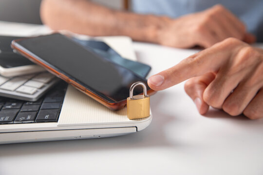 Male hand with a padlock, phones and computer keyboard. Internet and computer security