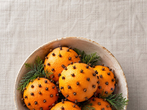 Clove studded orange pomanders in a ceramic bowl
