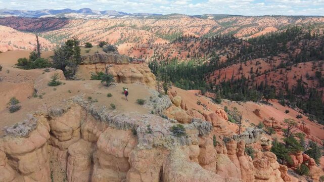Aerial view of man and woman hiking along the Buckhorn Trail in Utah, surrounded by hoodoos near Bryce Canyon. The landscape is vast and rocky