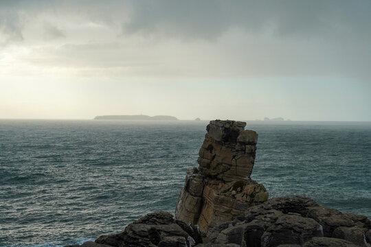 Dramatic view of Nau dos Corvos sea stack at Cabo Carvoeiro in Peniche, Portugal, under a stormy sky
