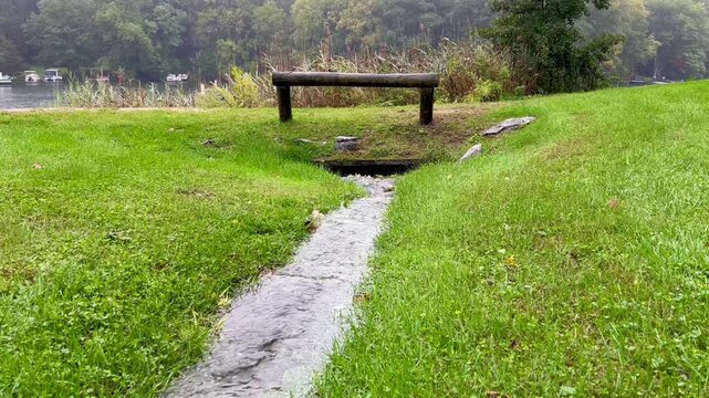 Water flowing through grassy drainage swale toward culvert 