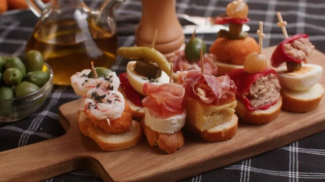 Tapas Spanish pinchos assortment, Basque pintxos with jamon iberico, tortilla, shrimp, stuffed piquillo pepper and egg on bread, traditional bar food close up