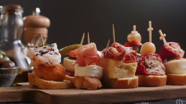 Tapas Spanish pinchos assortment, Basque pintxos with jamon iberico, tortilla, shrimp, stuffed piquillo pepper and egg on bread, traditional bar food close up