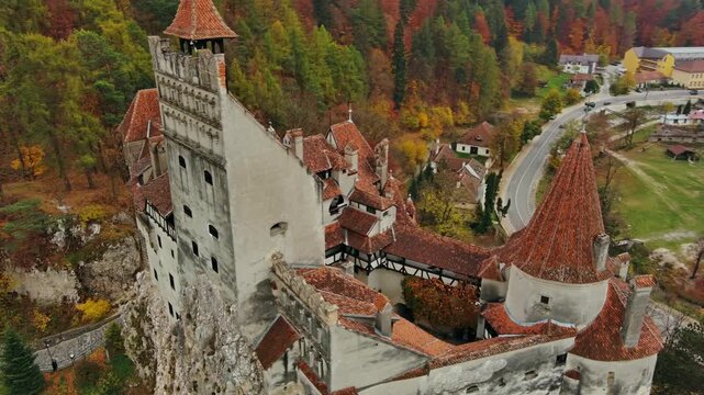 Aerial view of Bran Castle surrounded by colorful autumn forests and winding roads in Bran, Judetul Brasov, Romania.
