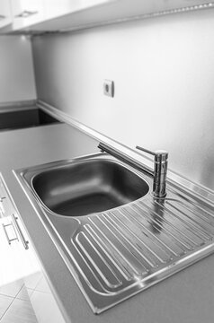 A modern chrome faucet and stainless steel sink are set into a sleek countertop in a contemporary kitchen.