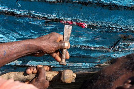 Vezo man caulking a wooden boat hull by hand, Belo sur Mer, Madagascar