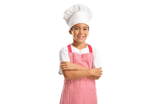 Little boy wearing a chef hat and a red striped apron and smiling with crossed arms