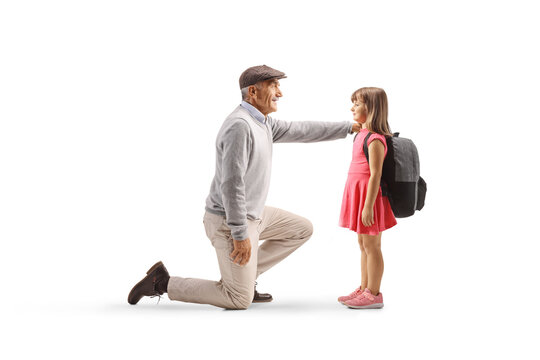 Elderly man kneeling on one knee and sending off a little girl with a backpack to school
