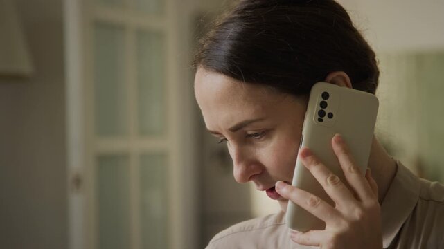 Caucasian mother talking on smartphone while soothing infant on lap during remote work. Clip suitable for marketing campaigns about maternity, parenting and telecommuting