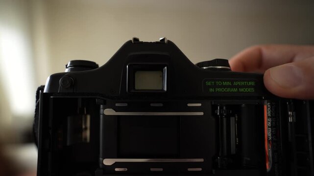 Taking photos inside the house with an analog camera; close-up shots of the camera from a POV perspective, interspersed with views of the camera's internal mechanical details
