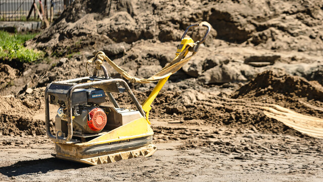 A machine is processing soil on a construction site. The area is busy with dirt and construction materials. Workers may be preparing for a new project
