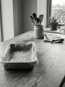 Parchment lined baking pan before wooden spoons in a ceramic crock in a kitchen