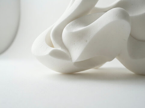 White abstract sculpture with intertwined flowing forms on a smooth surface