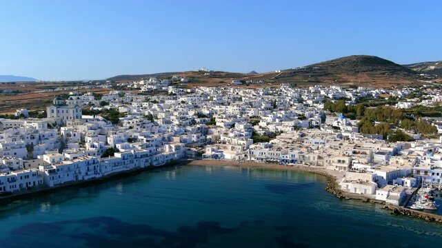 Aerial view of the coastal town of Naoussa with white buildings, a harbour, and clear blue sea in Islands, Greece.