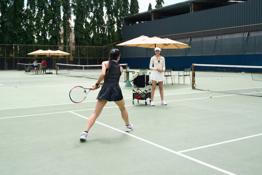 Woman Learning Tennis with Female Coach on Outdoor Court During Private Lesson