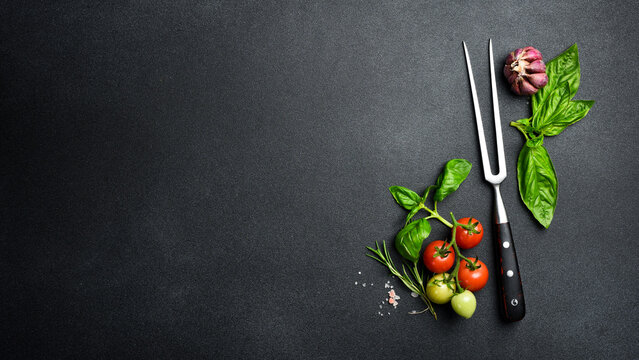 Background of the barbecue. Meat fork, kitchen utensils, salt, pepper and spices on table surface. Free space for text. Top view.