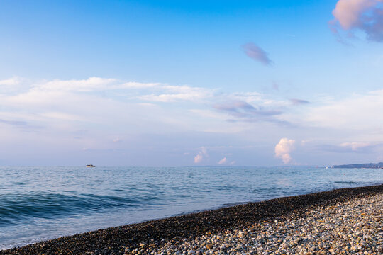 dark blue sky, sea water and pebble beach at dusk
