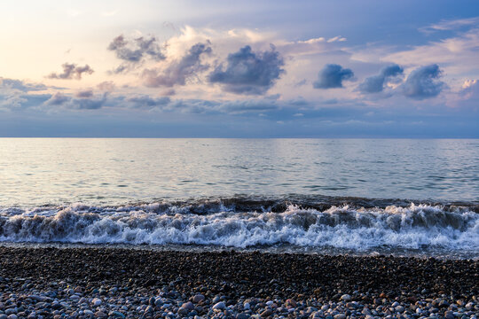 view of sea water surf from pebble beach at dusk