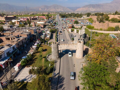 Aerial view of the historic Khyber Pass gate spanning the road with surrounding town buildings, mountain landscape, and vehicles in Khyber District, Khyber Pakhtunkhwa, Pakistan.