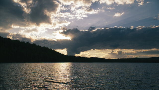 Dramatic Sunset Over Calm Lake and Wooded Hill, in sweden, smaland.