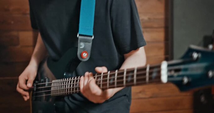 Close-up of a Musician's Hand Playing a Blue Electric Bass Guitar in a Professional Music Recording Studio