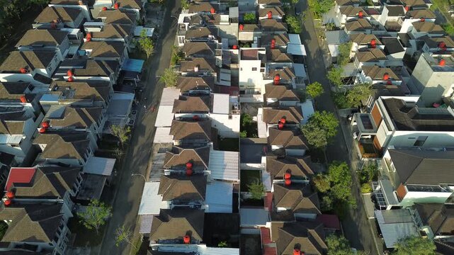 Aerial top down view of a dense modern residential housing complex in a suburban area with neat rows of houses, rooftops featuring orange water